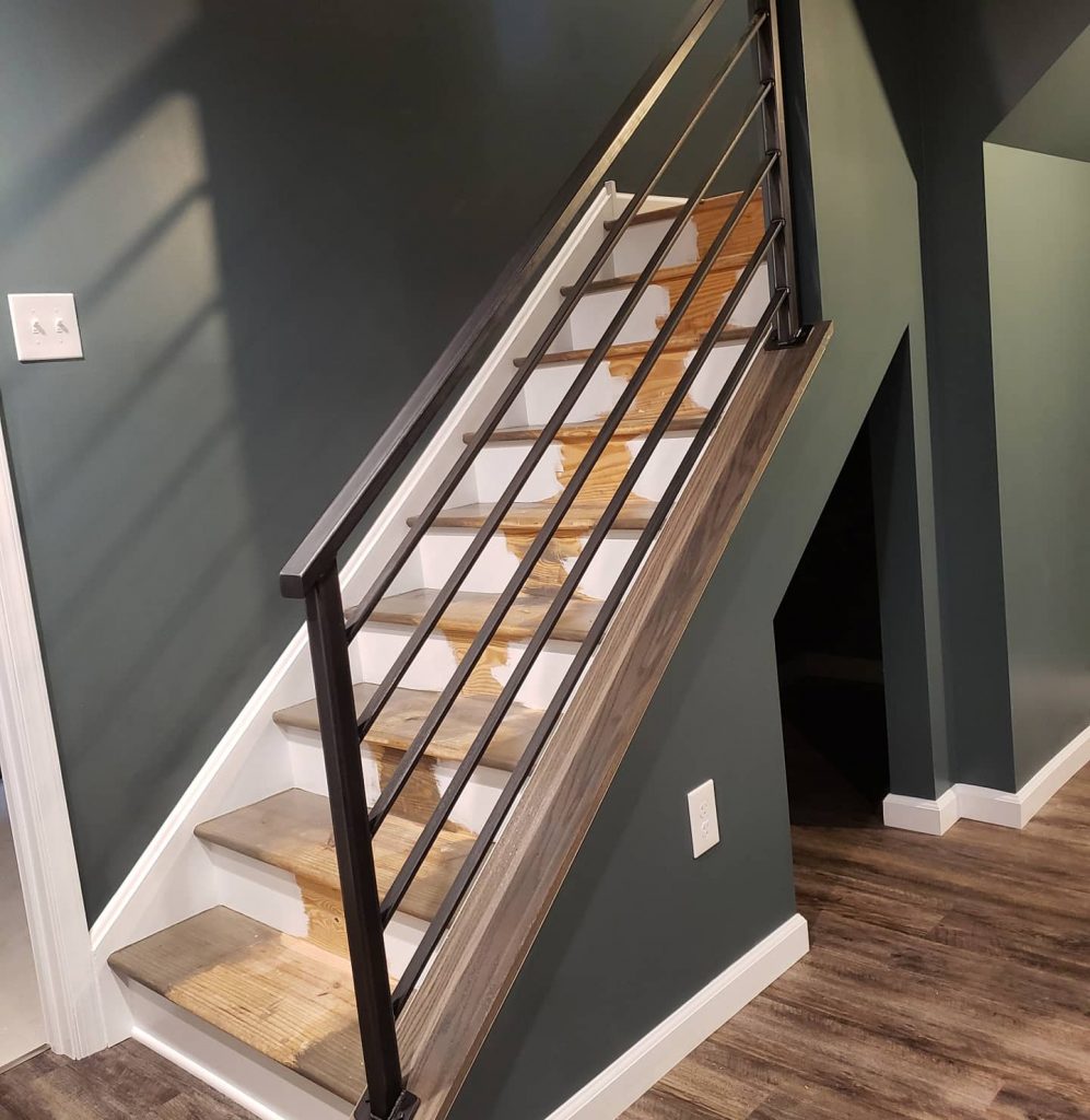 wood staircase with black railing, dark green wall